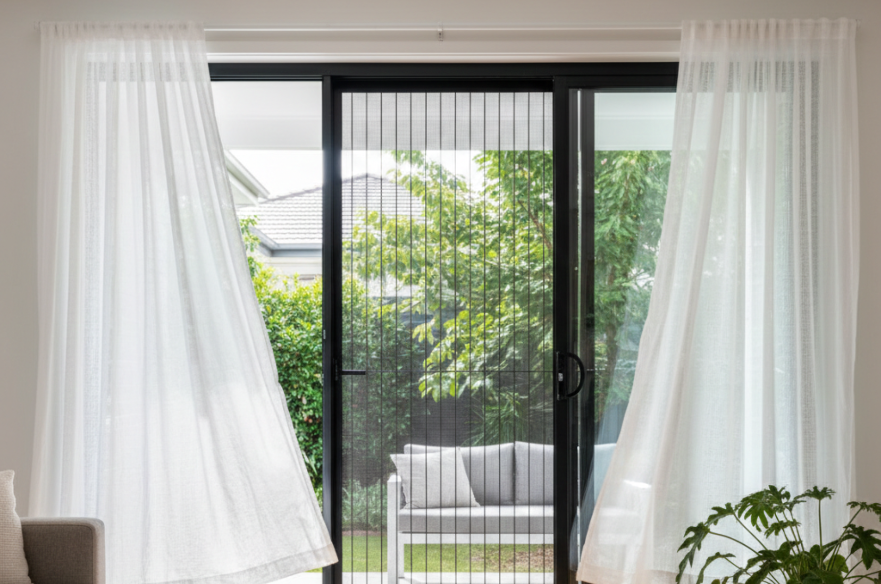 Bright Brisbane home with an open sliding door secured by a modern security screen, curtains moving in the summer breeze.